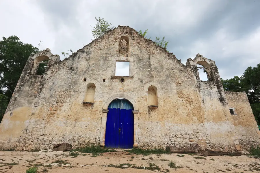 Iglesia de piedra en ruinas con una puerta azul, en Sacalaca
